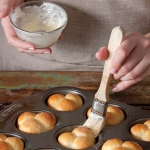 brushing baked rolls with butter